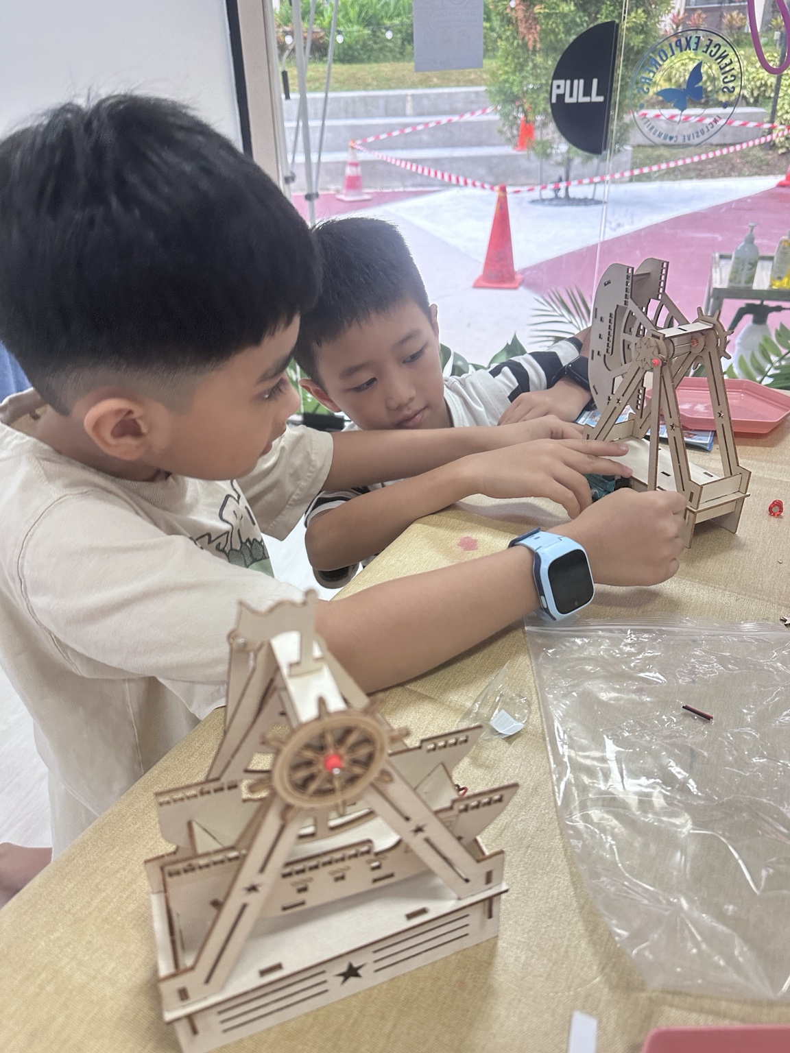 Two children exploring wooden wheel models together
